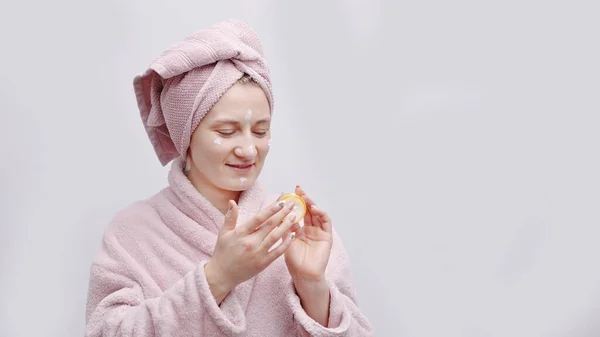 Meisje houden een kleine pot van hydraterende huid crème aanbrengen crème op haar gezicht — Stockfoto