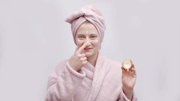 Meisje houden een kleine pot van hydraterende huid crème aanbrengen crème op haar neus — Stockfoto