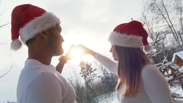 A young couple shows that it is brighter than the sky in the sign of the heart — Stock Video