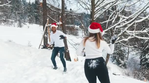 A young couple in love enjoys snowballing with a grandfathers hat on their head — Stock Video