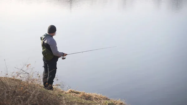 Un hombre vestido atléticamente con un bastón en la mano y un sombrero de invierno en la cabeza — Foto de Stock