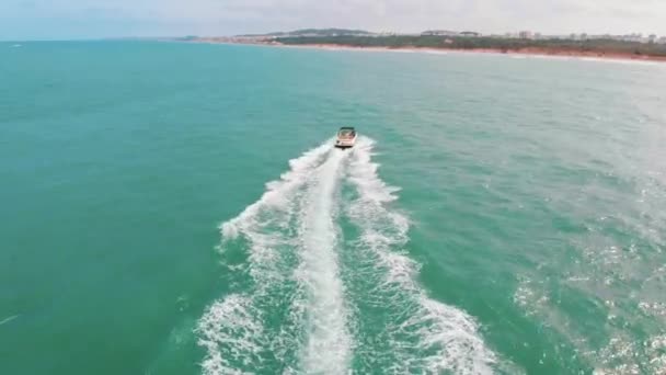 Motorcsónak távolodik a kamerától a Türkiz-tengeren habzó hullámokat csinál — Stock videók