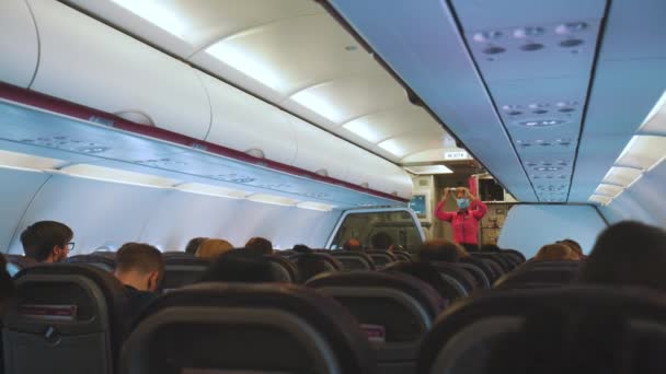Interieur van een vliegtuig met passagiers die passagiers instructies geven — Stockvideo