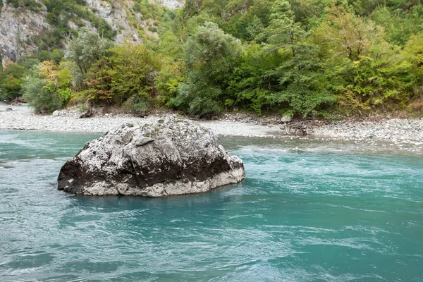Rivière de montagne turquoise et un grand rocher — Photo