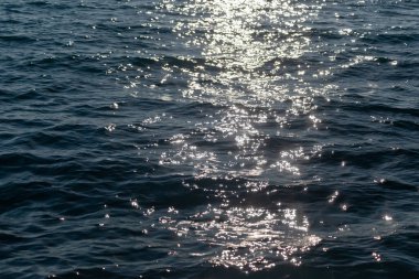 Yüzeyinde güneşli bir parıltı olan mavi deniz