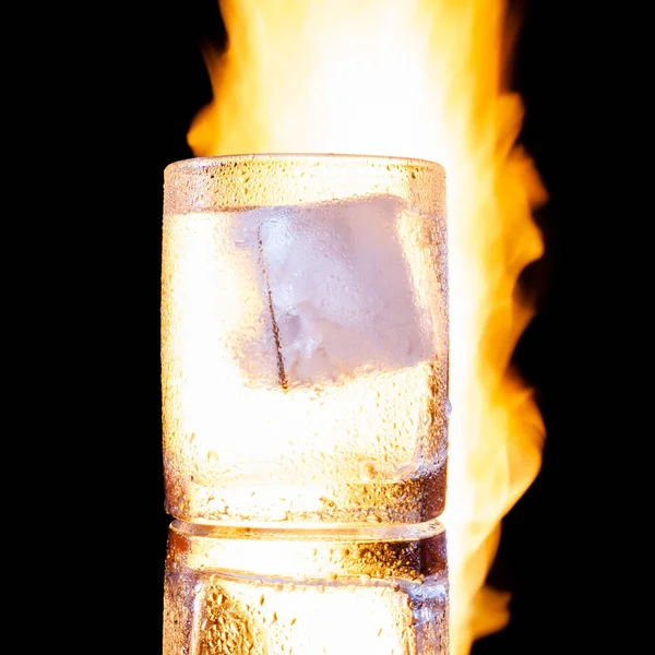 Glass of vodka with ice on fire on a black background — Stock Photo, Image