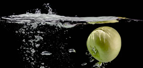 Świeże jabłko spada do wody z pęcherzykami powietrza, czarne tło, przestrzeń kopiowania — Zdjęcie stockowe
