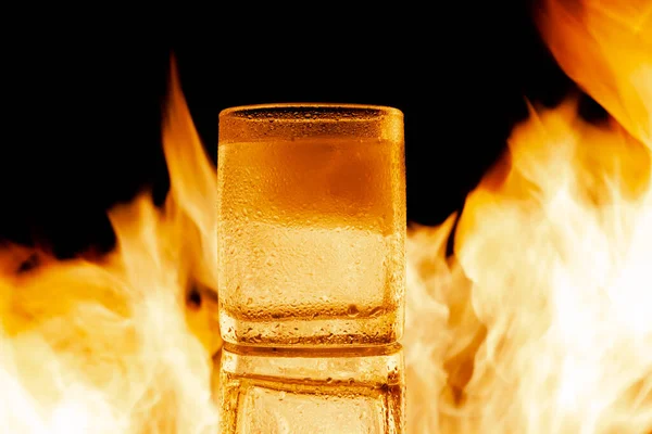 Verre de rhum avec glace contre les flammes — Photo