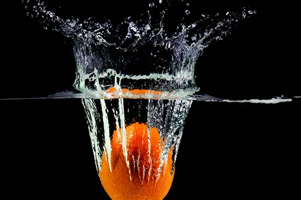 Φρούτα πορτοκαλί πέφτει στο νερό με πιτσιλιές σε μαύρο φόντο — Φωτογραφία Αρχείου