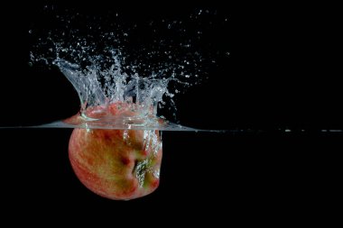 Siyah arkaplana su sıçratan kırmızı elma