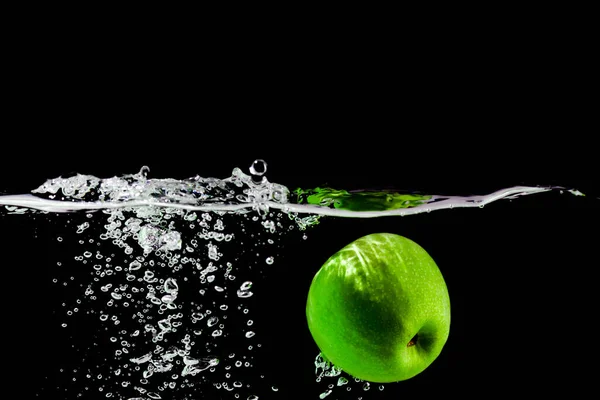 yeşil elma siyah arkaplanda suya düşer