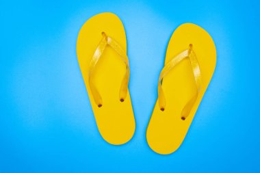 Sarı lastik parmak arası terlikler mavi arka planda izole edilmiş, bir çift tanga, yukarıda çekilmiş.