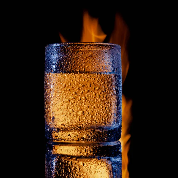 Sweating glass of water on fire on a black background — Stock Photo, Image
