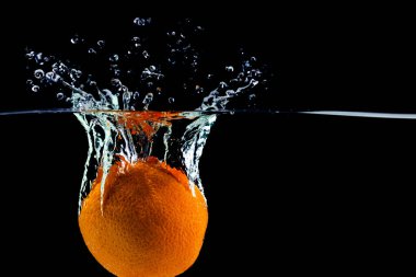 Bir portakal suya su sıçraması ve kabarcıklarla düştü.