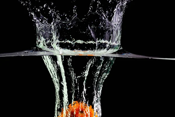 Фруктовий апельсин падає у воду з бризками на чорному тлі — стокове фото