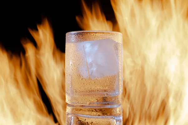 Sklenice brandy s ledem v ohni na černém pozadí — Stock fotografie