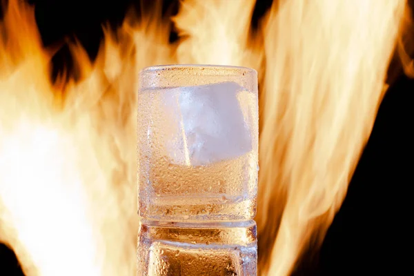 Sklenice vodky s ledem v ohni na černém pozadí — Stock fotografie