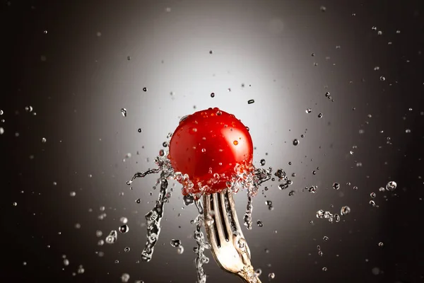 金属叉子上的樱桃西红柿。飞溅的水。黑色白色背景 — 图库照片