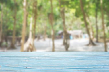 Bulanık plajda mavi ahşap masa ve arka planda palmiye ağaçları