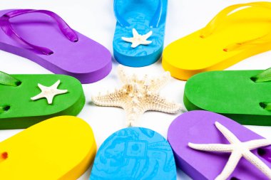 Beyaz arka planda üç çift plaj lastiği terliği.