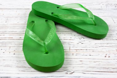 Beyaz ahşap arka planda yeşil lastik parmak arası terlikler