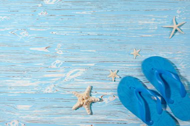 Deniz yıldızları ve kauçuk plaj mavi terlikler mavi ahşap arka planda