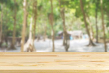 Bulanık sahildeki tahta masa ve arka planda palmiye ağaçları.