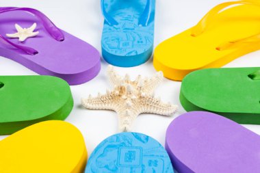 Beyaz arka planda deniz yıldızının etrafında çok renkli kauçuk plaj terlikleri