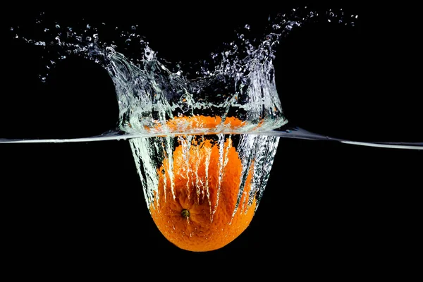 meyve portakalı suya düşer ve siyah arka planda sıçramalar olur.
