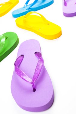Beyaz arka planda çok renkli lastik plaj terlikleri.