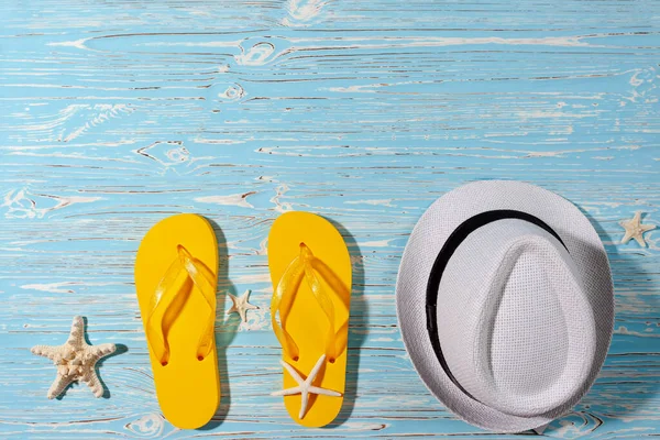 黄色橡胶翻盖，白色海滩帽，蓝木背景上的海星 — 图库照片
