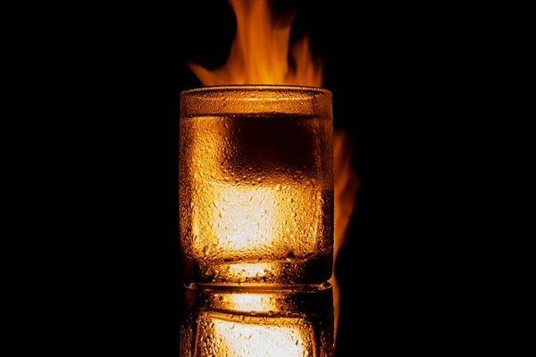 Brinnande glas alkohol med is på en svart bakgrund — Stockfoto