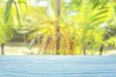 Bulanık tropikal bitki arka planında mavi tahta masa