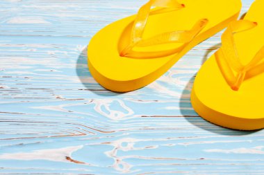 yellow flip flops on a blue wooden background, meesto under the text