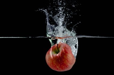Siyah arkaplana su sıçratan kırmızı elma