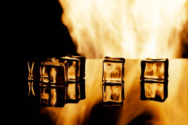 Cinco cubos de gelo sobre um fundo preto, nas chamas de fundo — Fotografia de Stock