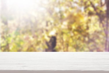 Bulanık sonbahar ormanı arka planında beyaz ahşap masa