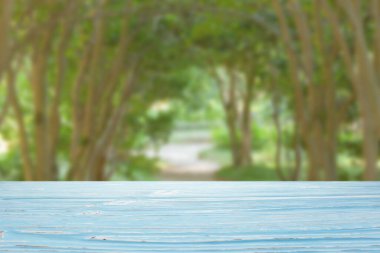 Ağaçların arkasındaki bulanık yeşil sokakta mavi ahşap masa.