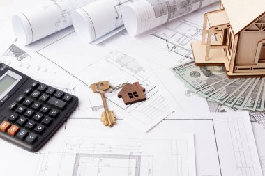 Evin çizimleri, dolar ve ahşap bir ev, hesap makinesi ve anahtarlık.
