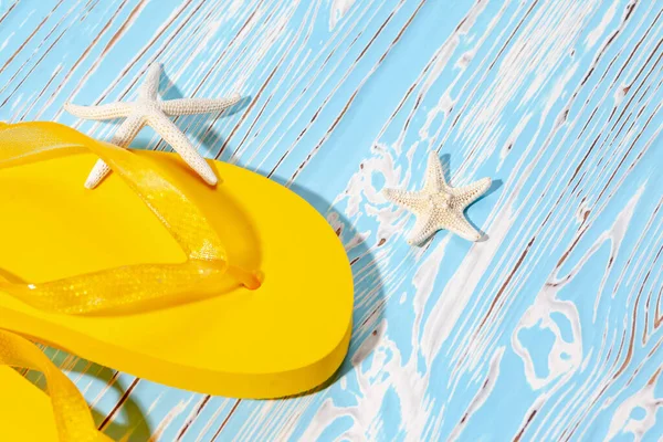 蓝色木制背景上的黄色橡胶海滩翻筋斗和海星，放在文本下面 — 图库照片