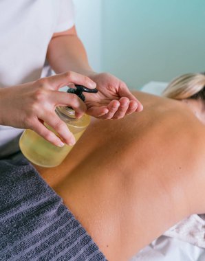 Fizyoterapist, yağlı genç bir kadına sırt masajı yapıyor. Bir kadının sırtına masaj yapan bir terapistin elleri.