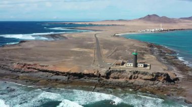 Ünlü Punta de Jandia Deniz feneri ve dolambaçlı erişim yolunun insansız hava aracı perspektifi Kanarya Adaları sahil şeridinin doğal güzelliğini ve izolasyonunu vurguluyor..