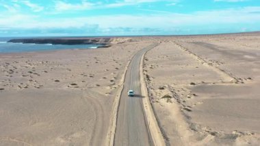 İnsansız hava aracı, batı Fuerteventura 'daki iki ünlü deniz fenerini birbirine bağlayan, dramatik volkanik manzaralar, sahil şeridi ve el değmemiş doğa gösteren toprak yol boyunca ilerleyen yalnız bir arabayı yakalıyor..