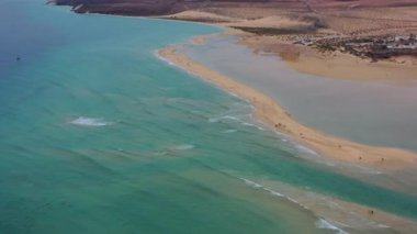 Fuerteventura, Kanarya Adaları 'ndaki Playa de la Barca' da yürüyen bir çiftin insansız hava aracı görüntüleri. Turkuaz okyanus, kıyı manzarası, seyahat ve romantik konsept