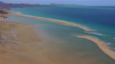 Fuerteventura, Kanarya Adaları 'ndaki Playa de la Barca' da yürüyen bir çiftin insansız hava aracı görüntüleri. Turkuaz okyanus, kıyı manzarası, seyahat ve romantik konsept
