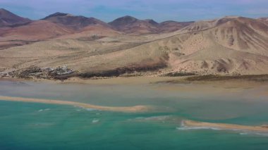 Fuerteventura, Kanarya Adaları 'ndaki Playa de la Barca' da çekilen hava görüntülerinde turkuaz sular, altın kum ve açık gökyüzü altında doğal kıyı oluşumları görülüyor..