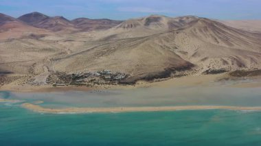Playa de la Barcas 'ın ikonik kum dilinin Atlantik Okyanusu' nun sığ lagünlerle buluştuğu yer olan Fuerteventura 'daki insansız hava aracı görüntüsü renk ve dokuların çarpıcı bir zıtlığını yaratıyor..