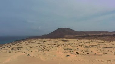 Kum tepeleri, düz bir yol ve Kanarya Adaları 'ndaki Corralejo Doğal Parkı' ndaki okyanus ufku olan hava manzarası..