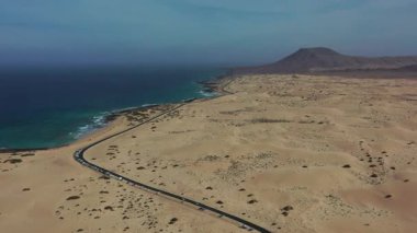 Parlak ve güneşli bir günde çekilen Corralejo Fuerteventura 'nın altın kum tepelerini kesen dolambaçlı bir yolun çarpıcı hava görüntüleri..
