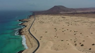 Corralejo 'da sonsuz kum tepeleriyle çevrili ıssız bir yolun yüksek açılı insansız hava aracı görüntüleri özgürlük, seyahat ve doğal güzelliği vurguluyor..